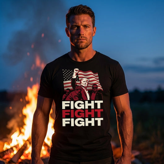 Man wearing Fight Fight Fight Trump black t-shirt by bonfire at dusk